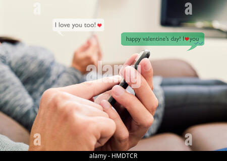 ein junger kaukasischen Mann und eine junge kaukasischen Frau senden und empfangen von SMS-Nachrichten in ihren Smartphones mit dem Text Happy Valentines Day, ich liebe Stockfoto