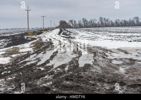 Landschaft mit schmutzigen Landstraße zwischen landwirtschaftlichen Feldern in der Zentralukraine am trüben Wintertag Stockfoto