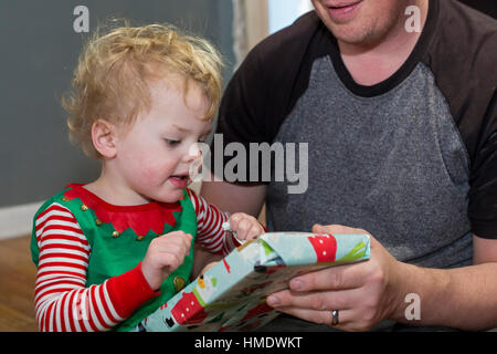 Denver, Colorado - Adam Hjermstad Jr., 2 1/2, öffnet sich ein Weihnachtsgeschenk von seinem Vater, Adam Hjermstad Sr. gehalten Stockfoto