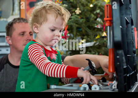 Denver, Colorado - Adam Hjermstad Jr., 2 1/2, spielt mit einem Werkzeugsatz bekam er zu Weihnachten, als sein Vater, Adam Hjermstad Sr., Uhren. Stockfoto