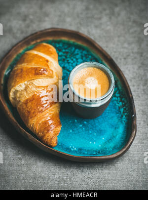 Espressokaffee und Croissant in Türkis Blau Keramik Schale über graue konkreten Hintergrund, selektiven Fokus Stockfoto