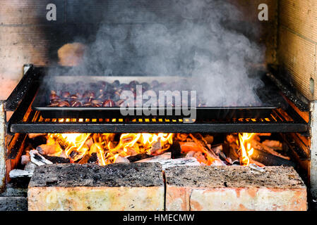 Rösten Kastanien am Grill mit Holzkohle, Flammen und Feuer gegrillt. Hausgemachte gebratene Kastanien sind im BBQ Grill Kamin bereit. Stockfoto