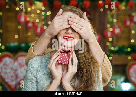 Mann ein Geschenk für ihre Freundin. Wunderschöne Brautpaar. junge schließt Mädchen Augen seine Handflächen Stockfoto