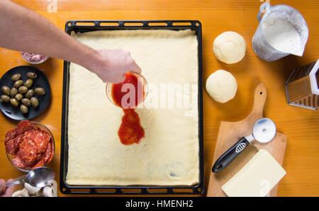 Mann, der Tomatensauce auf rohe Pizza base Stockfoto