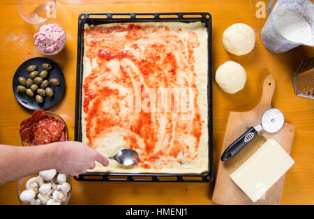 Mann, der Tomatensauce auf rohe Pizza base Stockfoto