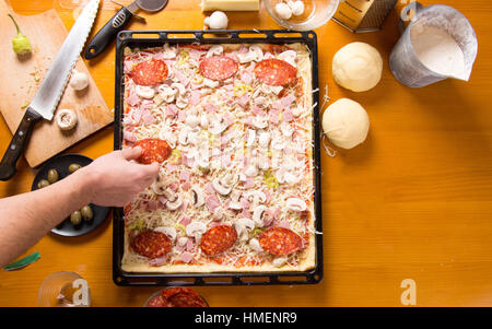 Männlichen Chef Pizza auf einer Pfanne Zutaten hinzufügen Stockfoto