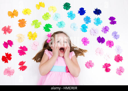 Kleines Mädchen in rosa Pastell Kleid Auswahl bunter Haarschmuck. Bogen und Farbband für Kinder. Frisur und Zubehör für Kinder Stockfoto