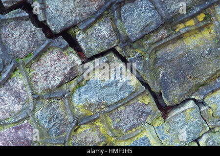 ein Riss in der Wand, grünes Moos bedeckt die alte Steinmauer Stockfoto