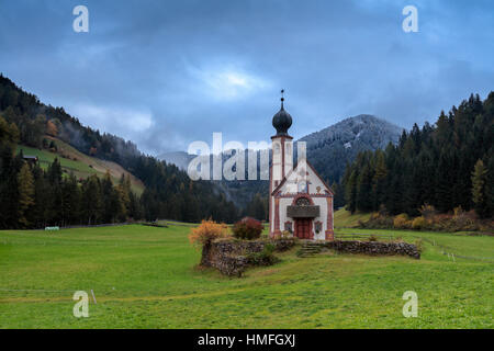 Wolken auf Kirche von Ranui, umgeben von Wiesen und Wäldern im Herbst, St.Magdalena, Villnösser Tal, Südtirol, Dolomiten, Italien Stockfoto