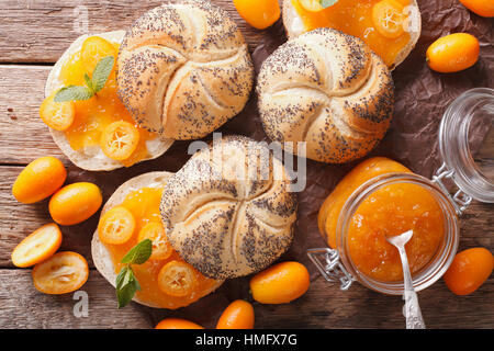 Kumquat-Marmelade in ein Glas Jar und süße Brötchen Nahaufnahme auf dem Tisch. Horizontale Ansicht von oben Stockfoto