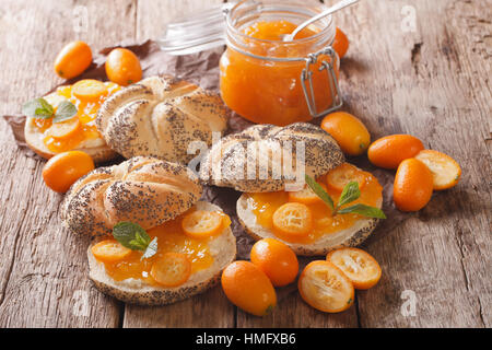 Kumquat-Marmelade in ein Glas Jar und süße Brötchen Nahaufnahme auf dem Tisch. horizontale Stockfoto