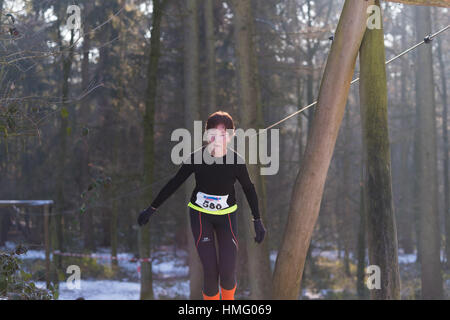 OLDENZAAL, Niederlande - 22. Januar 2017: Unbekannte Sportlerin tut ein Kreuz in einem verschneiten Wald laufen Stockfoto