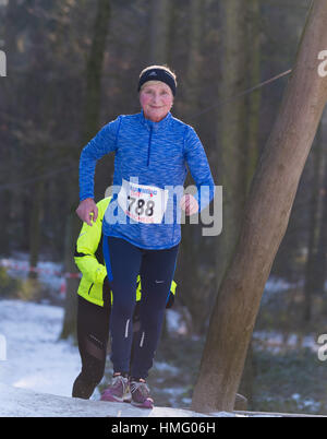 OLDENZAAL, Niederlande - 22. Januar 2017: Unbekannte Sportlerin tut ein Kreuz in einem verschneiten Wald laufen Stockfoto