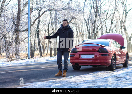 Mann Probleme mit gebrochenen Sportwagen auf Winterdienst-Signalisierung. Stockfoto