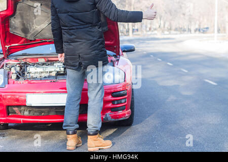 Mann Probleme mit gebrochenen Sportwagen auf Winterdienst-Signalisierung. Stockfoto