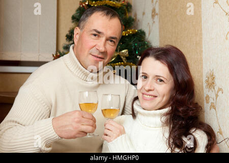 Weihnachten Couple.Happy lächelnd Familie zu Hause feiern. Neue Jahr Menschen. Paar mittleren Alters in der Nähe von einem Weihnachtsbaum mit Glas Champagner im Inneren des Hauses Stockfoto