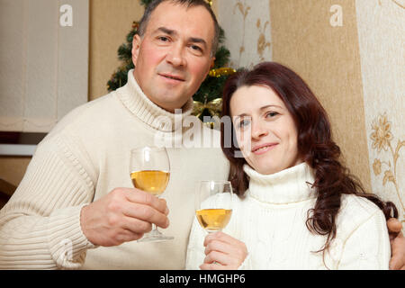 Weihnachten Couple.Happy lächelnd Familie zu Hause feiern. Neue Jahr Menschen. Paar mittleren Alters in der Nähe von einem Weihnachtsbaum mit Glas Champagner im Inneren des Hauses Stockfoto