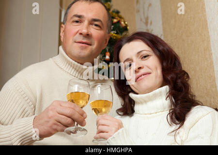 Weihnachten Couple.Happy lächelnd Familie zu Hause feiern. Neue Jahr Menschen. Paar mittleren Alters in der Nähe von einem Weihnachtsbaum mit Glas Champagner im Inneren des Hauses Stockfoto