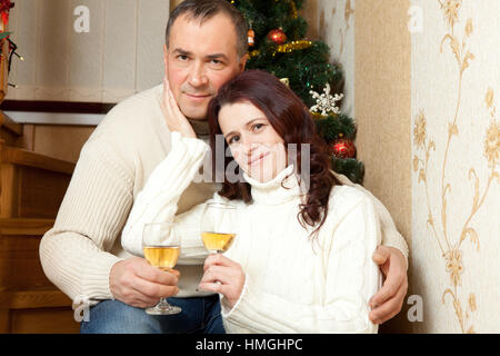 Weihnachten Couple.Happy lächelnd Familie zu Hause feiern. Neue Jahr Menschen. Paar mittleren Alters in der Nähe von einem Weihnachtsbaum mit Glas Champagner im Inneren des Hauses Stockfoto