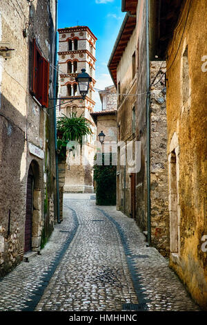 Schmale Straße mit Kopfsteinpflaster in einer mittelalterlichen Stadt führt zu einem Glockenturm, Sermoneta, Latium, Italien Stockfoto