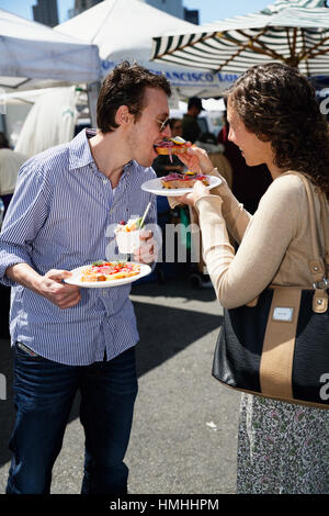 Junges Paar teilen Essen zu einem Straßenfest, San Francisco, Kalifornien Stockfoto