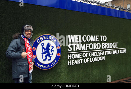 Ein Fan posiert für ein Foto neben der "Willkommen an der Stamford Bridge" Schild vor dem Premier League-Spiel zwischen Chelsea und Arsenal. Stockfoto