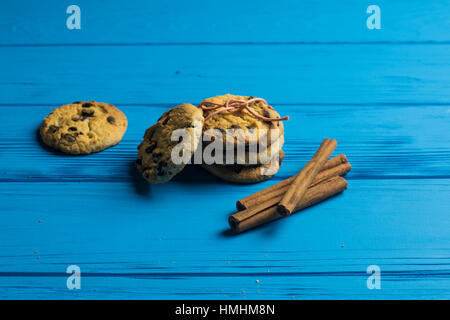 Kekse mit Schokolade und Zimt-Sticks auf blauem Hintergrund aus Holz Stockfoto