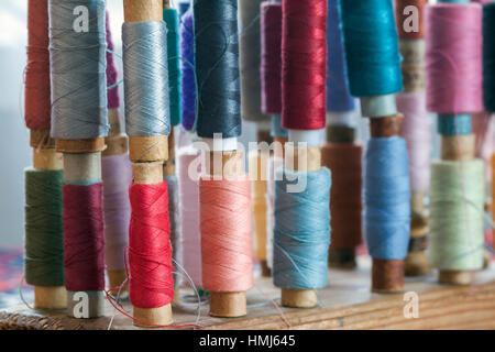 Mehrfarbige Nähgarne Vintage weiche Pastellfarben auf Spulen. Nähen-Schneider im Zusammenhang mit Zubehör. Stockfoto