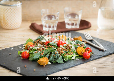 Salat mit Falafel, Linsen und gebackene Tomaten auf Steinplatte serviert Stockfoto