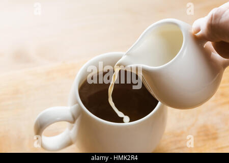 Nahaufnahme in Tasse heißen Kaffee Sahne gießen. Stockfoto