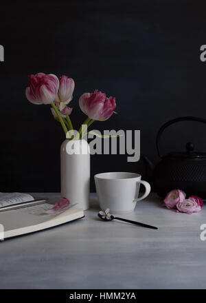 Stillleben mit rosa doppelte Tulpen in weiße kleine Keramik-Vase mit Becher und Löffel, low-key Stockfoto