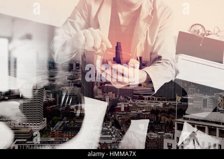 Doppelbelichtung junger Mann sitzt auf einem Sofa Online shopping ist Musik mit Kopfhörern hören hält Smartphone auf seine Seite zu Hause, Omni Stockfoto