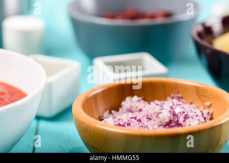 Gehackte rote Zwiebeln und Lebensmittelzutaten auf Türkis Küchentisch Stockfoto