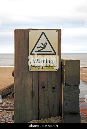 Eine rutschige Oberfläche Warnschild am Strand von Mundesley-on-Sea, Norfolk, England, Vereinigtes Königreich. Stockfoto