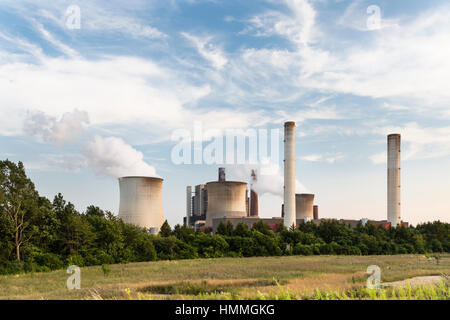 Eine große Kohle-Kraftwerk hinter einigen Bäumen und einem Feld. Stockfoto