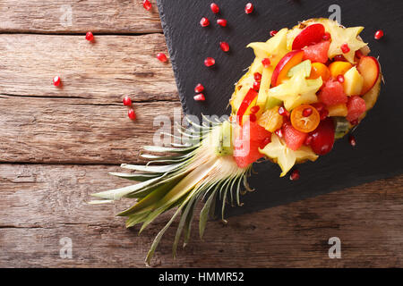 Ananas gefüllt mit frischen exotischen Früchten Nahaufnahme auf dem Tisch. horizontale Ansicht von oben Stockfoto