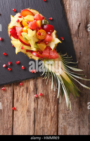 Ananas gefüllt mit frischen exotischen Früchten Nahaufnahme auf dem Tisch. vertikale Ansicht von oben Stockfoto