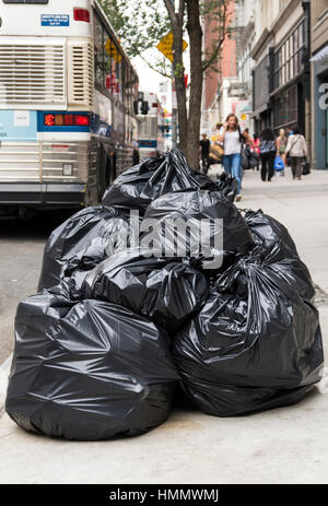 Berge von Müll in schwarzen Mülltüten aufgestapelt auf dem Bürgersteig erwartet Sammlung in einer Straße in New York Stockfoto