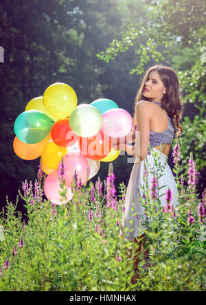 Mädchen in der Natur hält Luftballons weiße Kleid Stockfoto