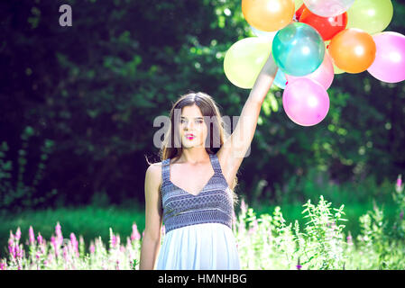 Mädchen in der Natur hält Luftballons weiße Kleid Stockfoto