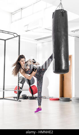 Hübsche Brünette Frau Kickboxen high Kicks trainieren im modernen Fitnesscenter. Stockfoto