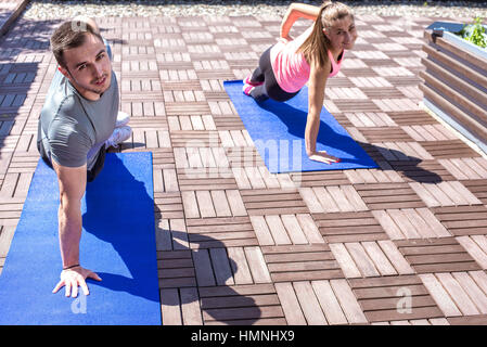 Junges Paar Seite Plank gemeinsam ausüben, auf dem Dach im Freien. Stockfoto