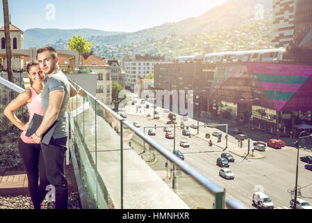 Jungen Erwachsenen weiblichen Fitness Model posiert auf Dachterrasse mit ihrem persönlichen Trainer anschließend Fitness-Übungen. Stockfoto