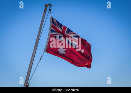 Australian Red Ensign Fahne am Mast vor blauem Himmelshintergrund Stockfoto