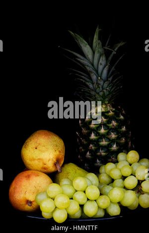 Obstteller mit Ananas, Birnen und Trauben. Stockfoto