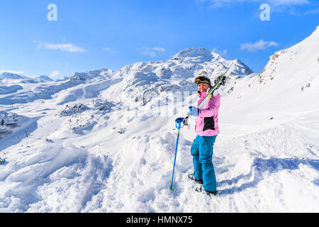 Junge Frau Skifahrer stehen und hält Ski in Obertauern Winter Mountain Resort, Österreich Stockfoto