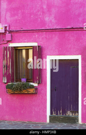 Abblätternde Farbe auf Tür und Fensterläden von lila rosa Gebäude in Burano, Venedig, Italien im Januar Stockfoto