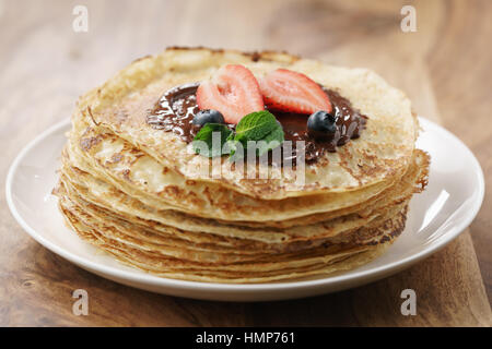 frische Blinis oder Crepes mit geschmolzener Zartbitterschokolade und Beeren Stockfoto