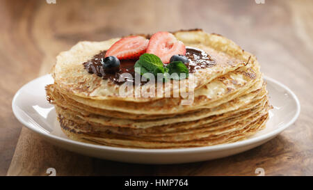 frische Blinis oder Crepes mit geschmolzener Zartbitterschokolade und Beeren Stockfoto