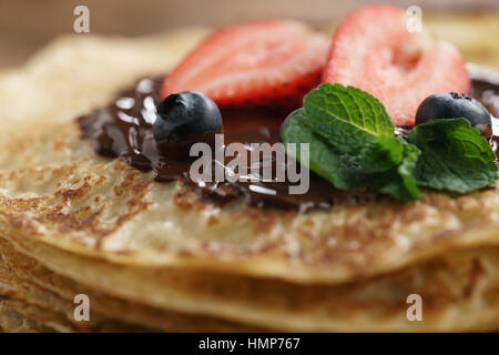 frische Blinis oder Crepes mit geschmolzener Zartbitterschokolade und Beeren Stockfoto